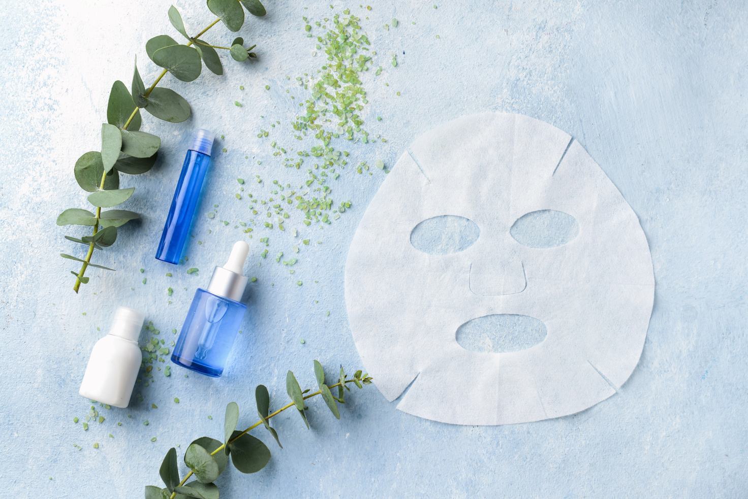 Sheet Facial Mask with Cosmetic Products on Color Background